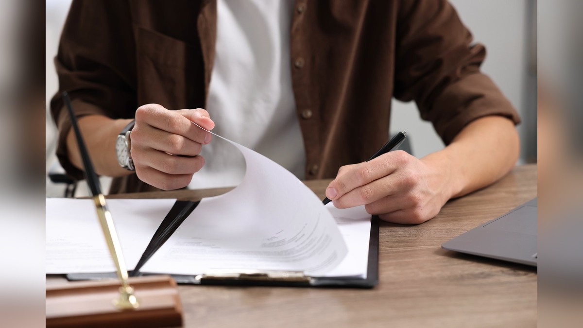 A person checking pages of an official document at a desk before submitting it for attestation
