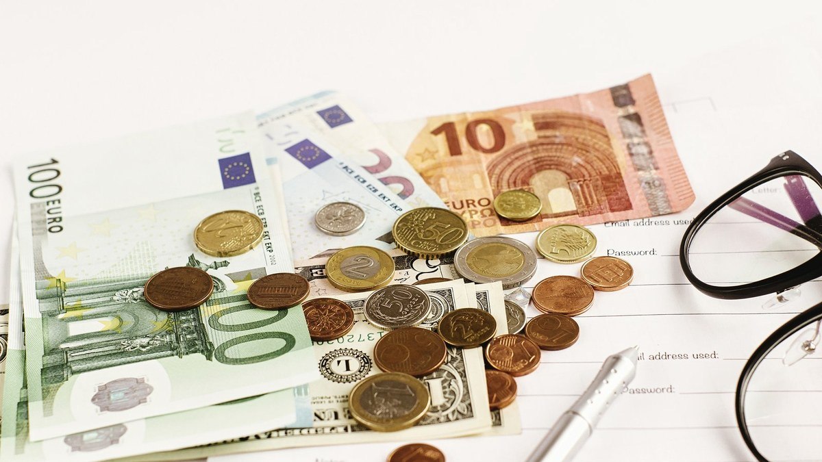 Euro banknotes and coins beside a paper application form, illustrating the blocked-account funds a German student visa requires