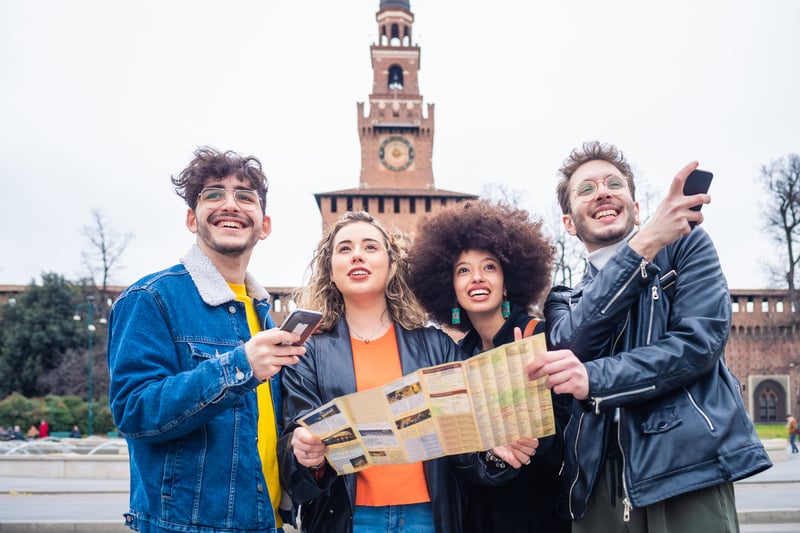 International students with a paper city map in front of Sforza Castle in Milan, finding their way in the first week after arrival