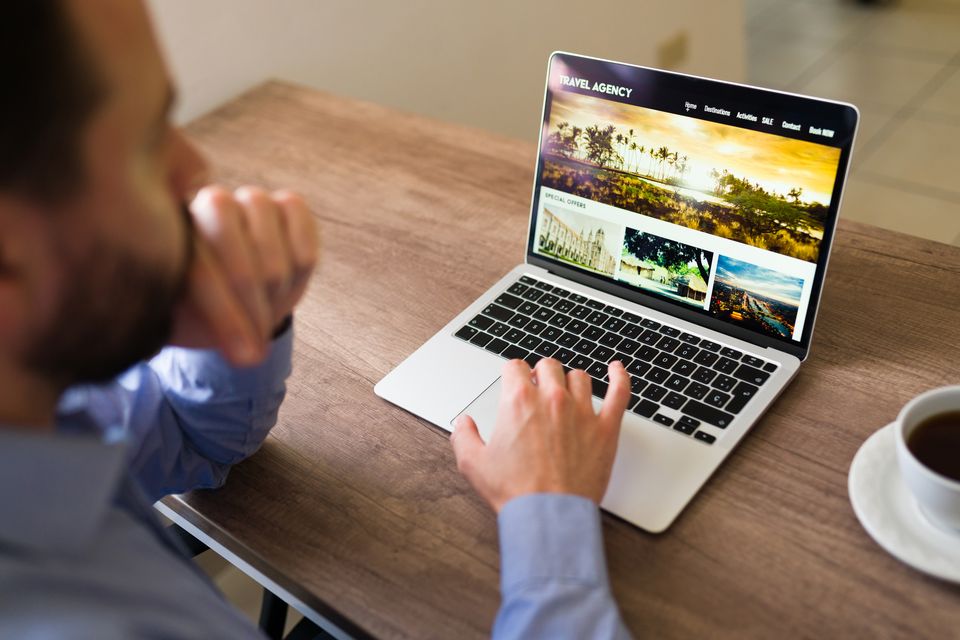 Hombre revisa en su laptop el diseño del sitio web de una agencia de viajes