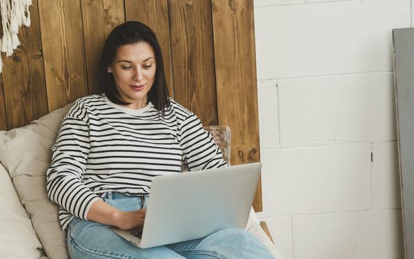 Mujer crea su sitio web desde la laptop en la sala de su casa