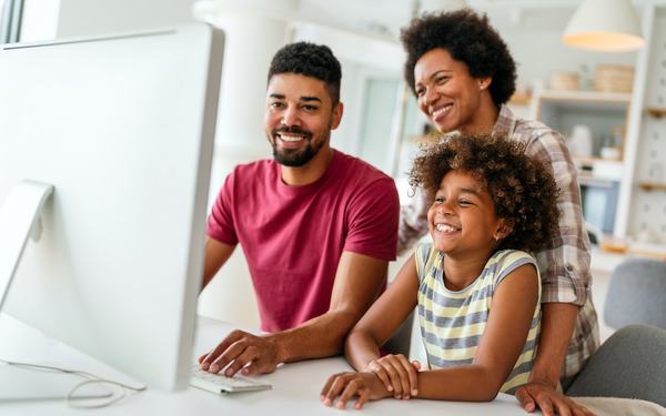 Familia sonriente revisa un sitio web en la computadora de casa